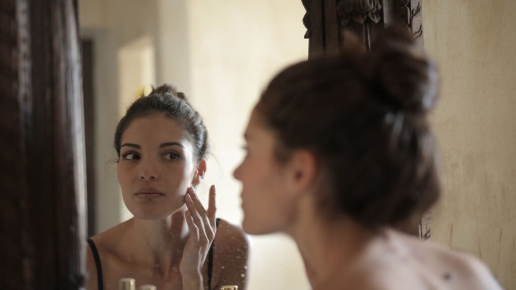 Mulher observando o próprio rosto no espelho antes da reversão harmonização facial